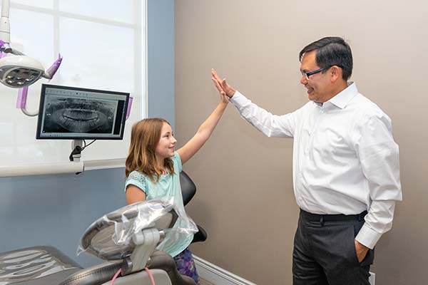 [[[cspa:doc1]]] high-fiving a kid after fixing her mouth guard.