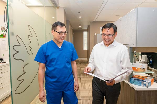 Drs. Lee walking in the hallway looking at a file.