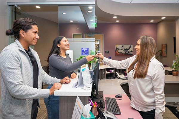 A receptionist shaking hands with a patient at Picasso Dental Care.