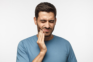 male patient holding his hand up to his face and grimacing with pain