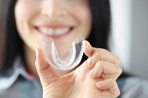 Close up of a simple mouth guard being held up by an excited woman Picasso Dental Care in Temecula, CA Close up of a simple mouth guard being held up by an excited woman Picasso Dental Care in Temecula, CA