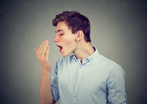 young adult checking for bad breath with eyes closed